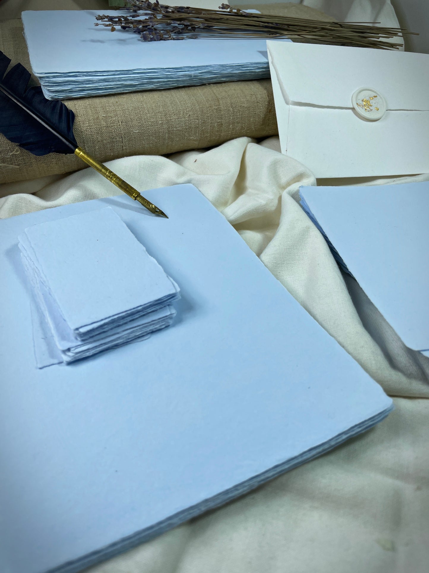 dekoratives Arrangement von blauem, handgeschöpften Büttenpapier mit Schreibfeder