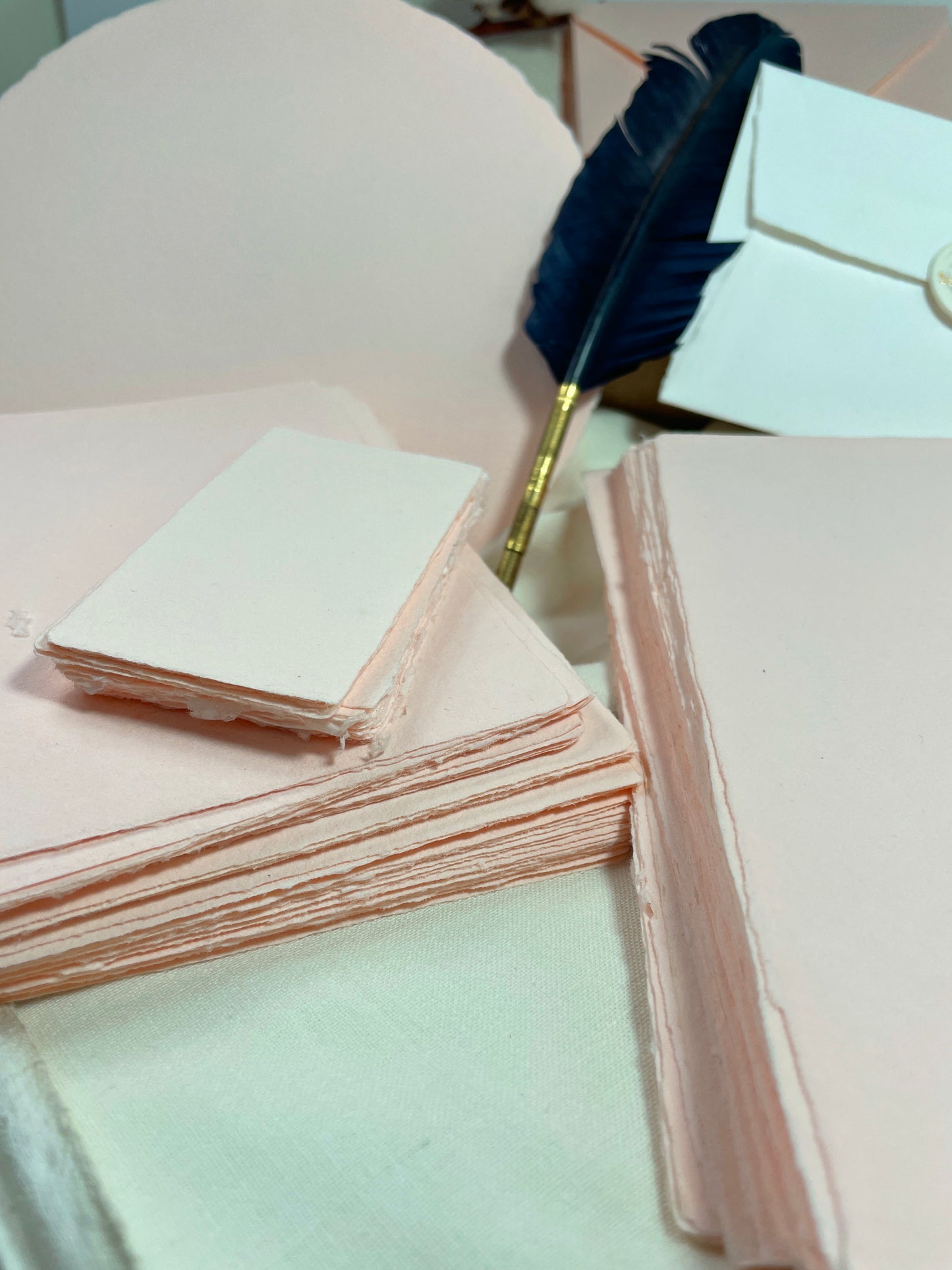 dekoratives Arrangement von rosafarbenem Büttenpapier mit Schreibfeder und Blumen