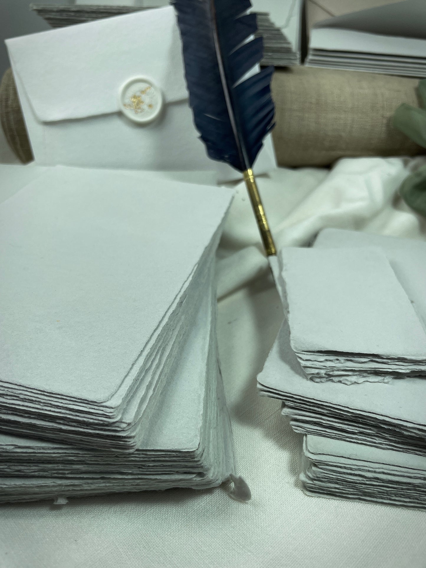 dekoratives Arrangement von grauem Büttenpapier mit Schreibfeder