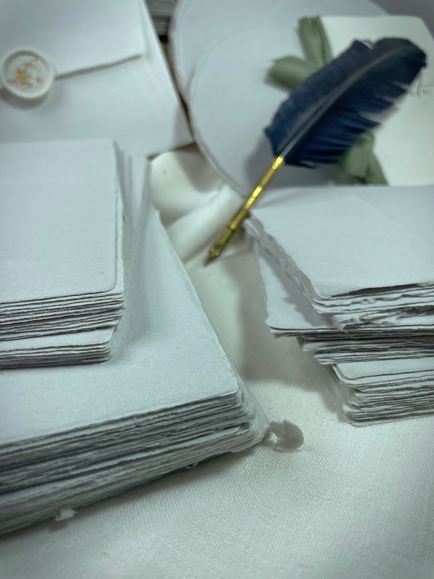 dekoratives Arrangement von grauem Büttenpapier mit Schreibfeder
