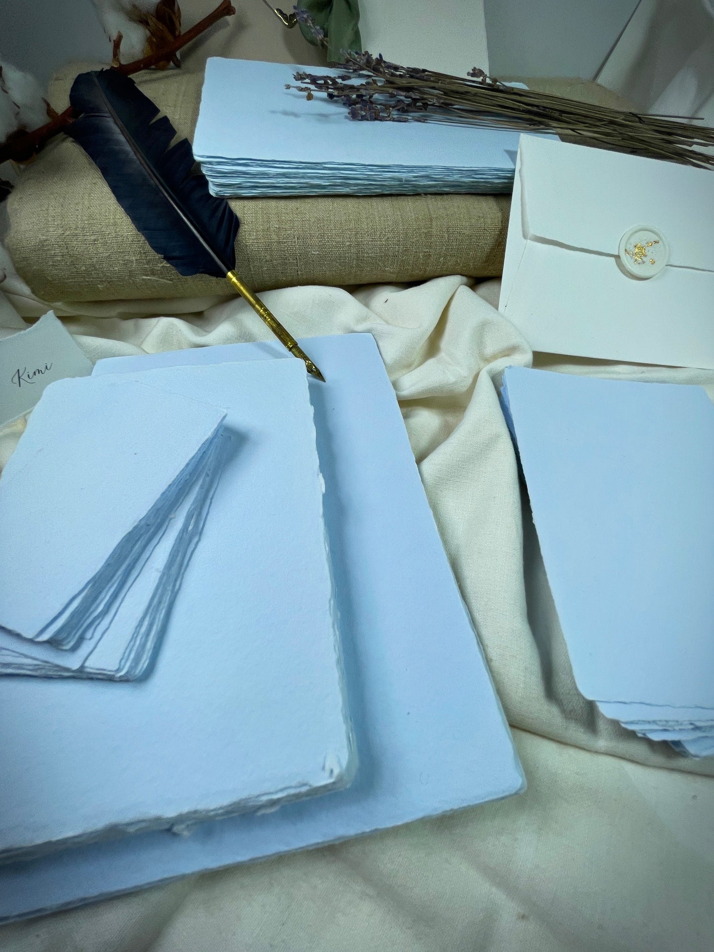 dekoratives Arrangement von blauem, handgeschöpften Büttenpapier mit Schreibfeder