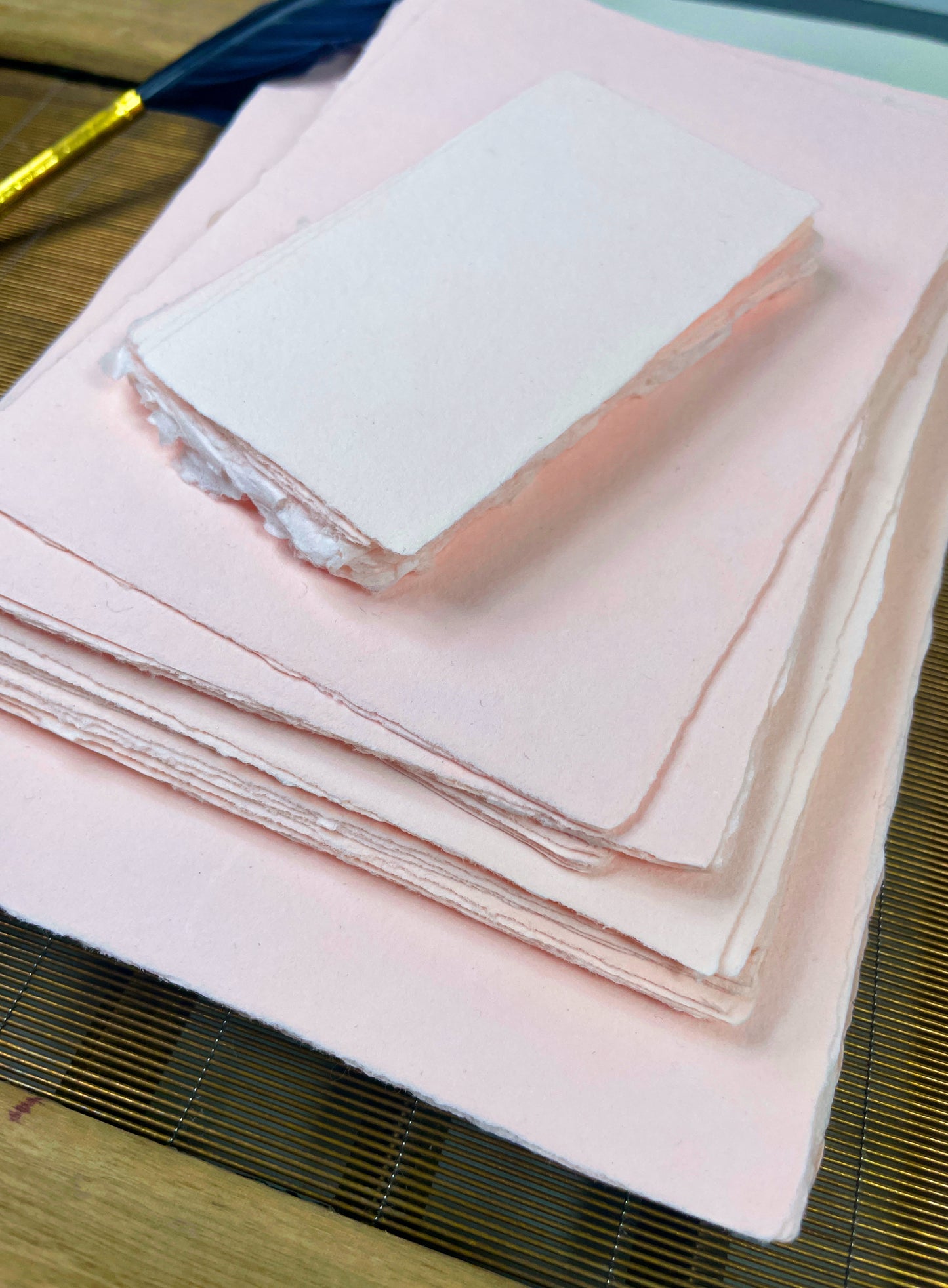 dekoratives Arrangement von rosafarbenem Büttenpapier mit Schreibfeder 
