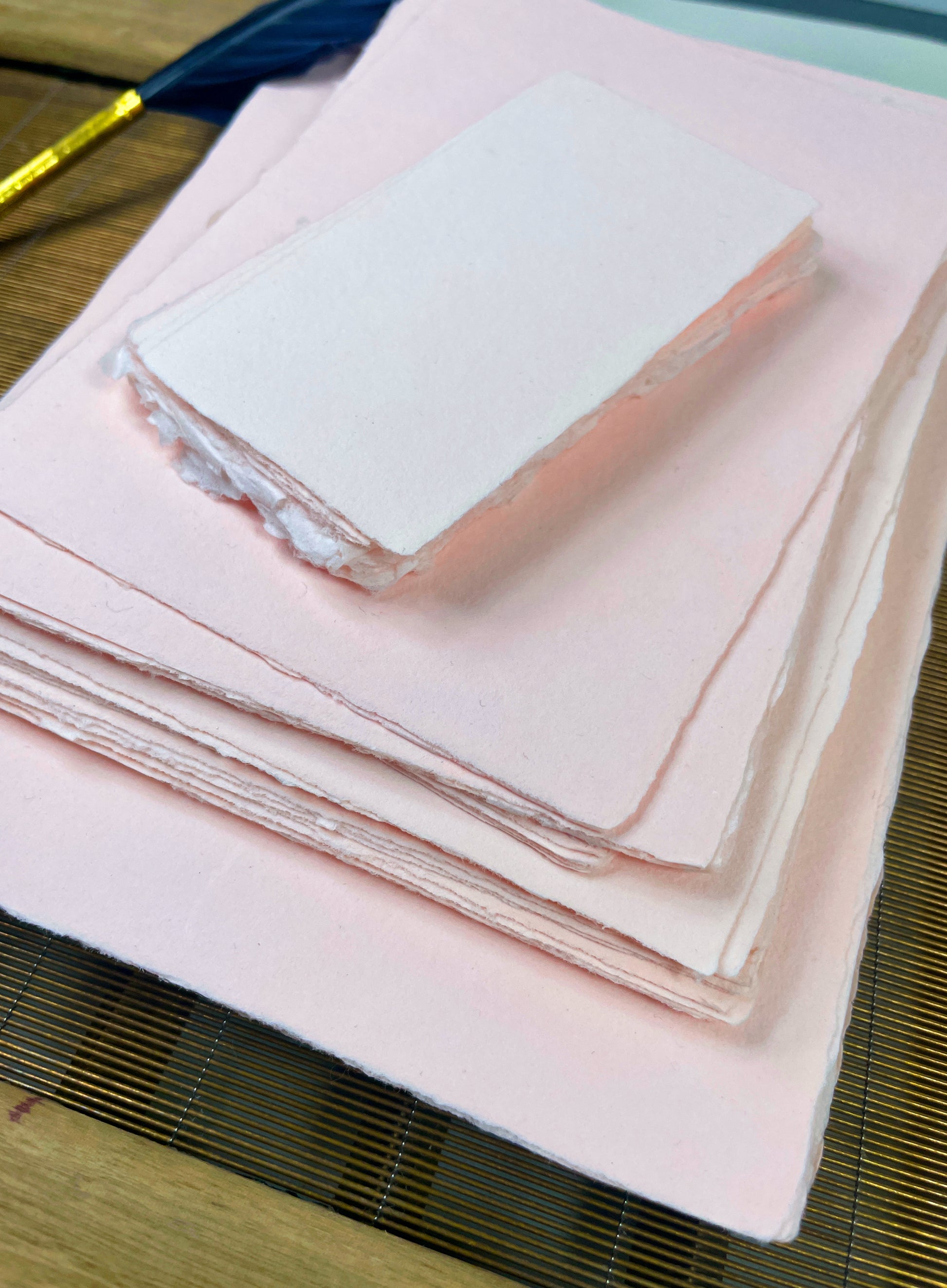 dekoratives Arrangement von rosafarbenem Büttenpapier mit Schreibfeder 