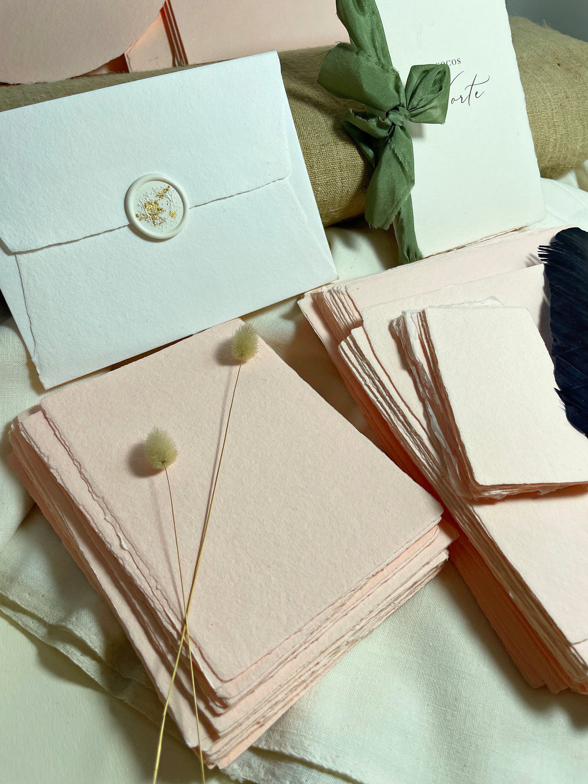 dekoratives Arrangement von rosafarbenem Büttenpapier mit Schreibfeder und Blumen