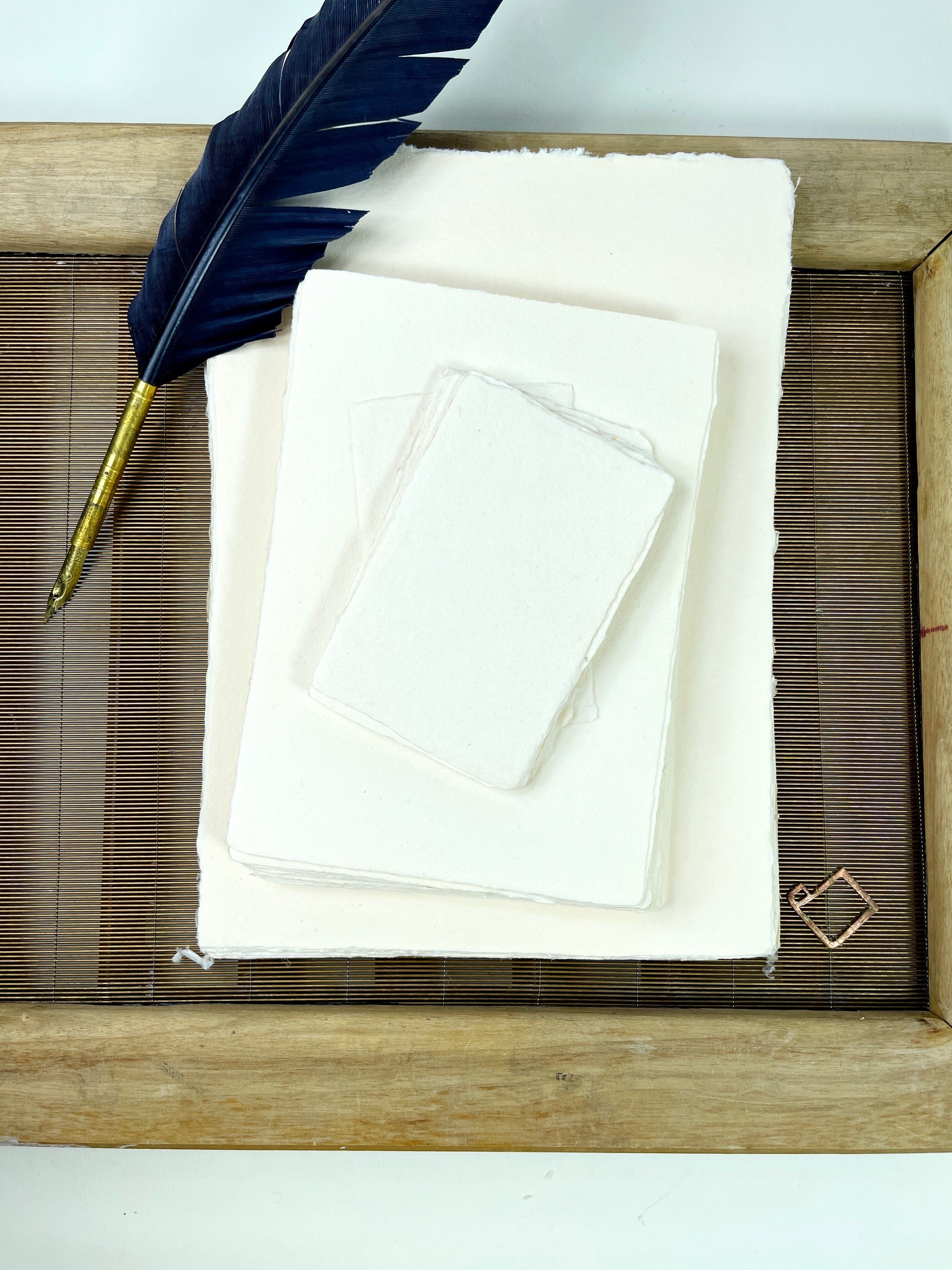 dekoratives Arrangement von cremefarbenem Büttenpapier mit Schreibfeder
