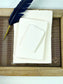 dekoratives Arrangement von cremefarbenem Büttenpapier mit Schreibfeder