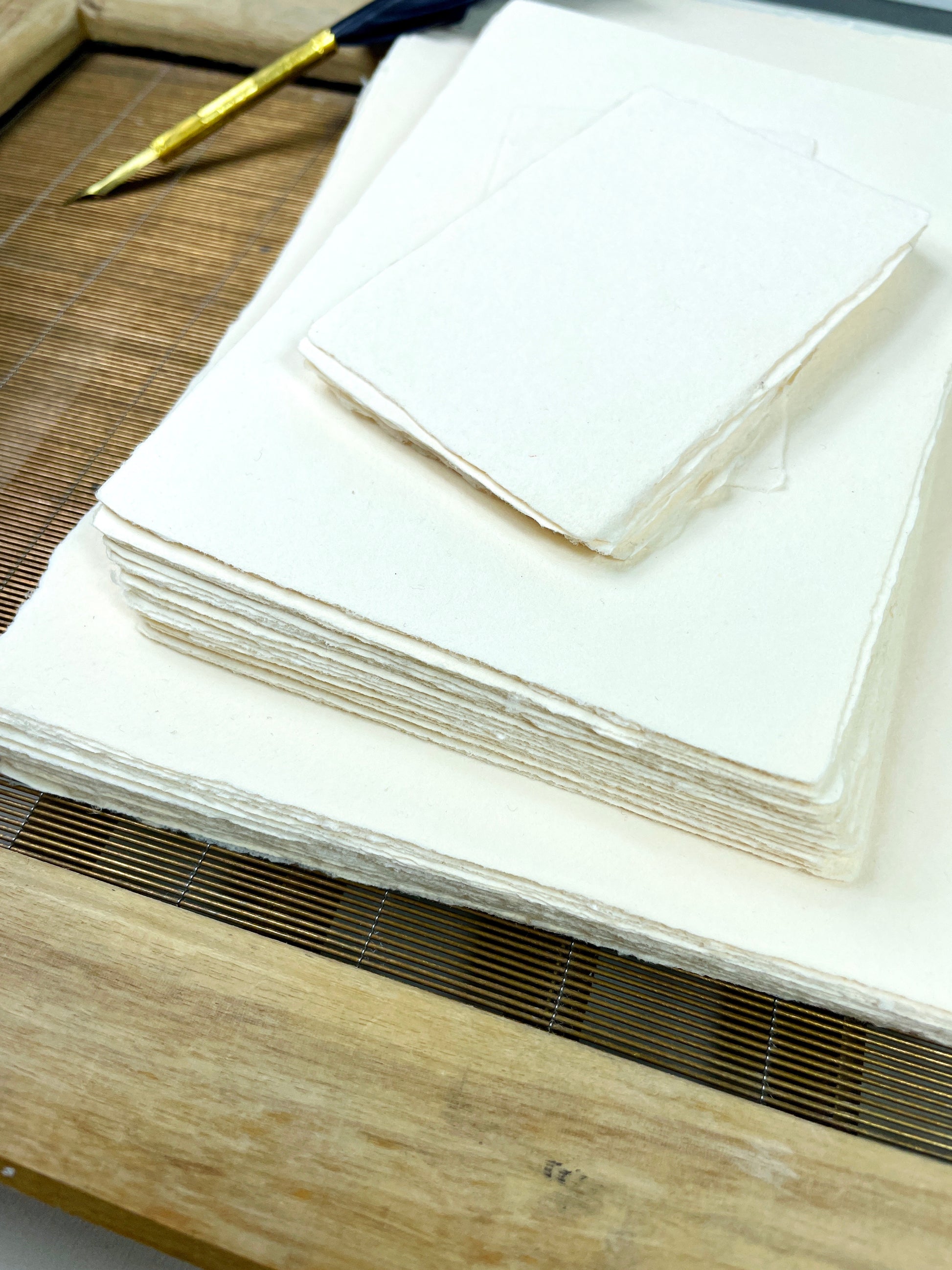 dekoratives Arrangement von cremefarbenem Büttenpapier mit Schreibfeder 