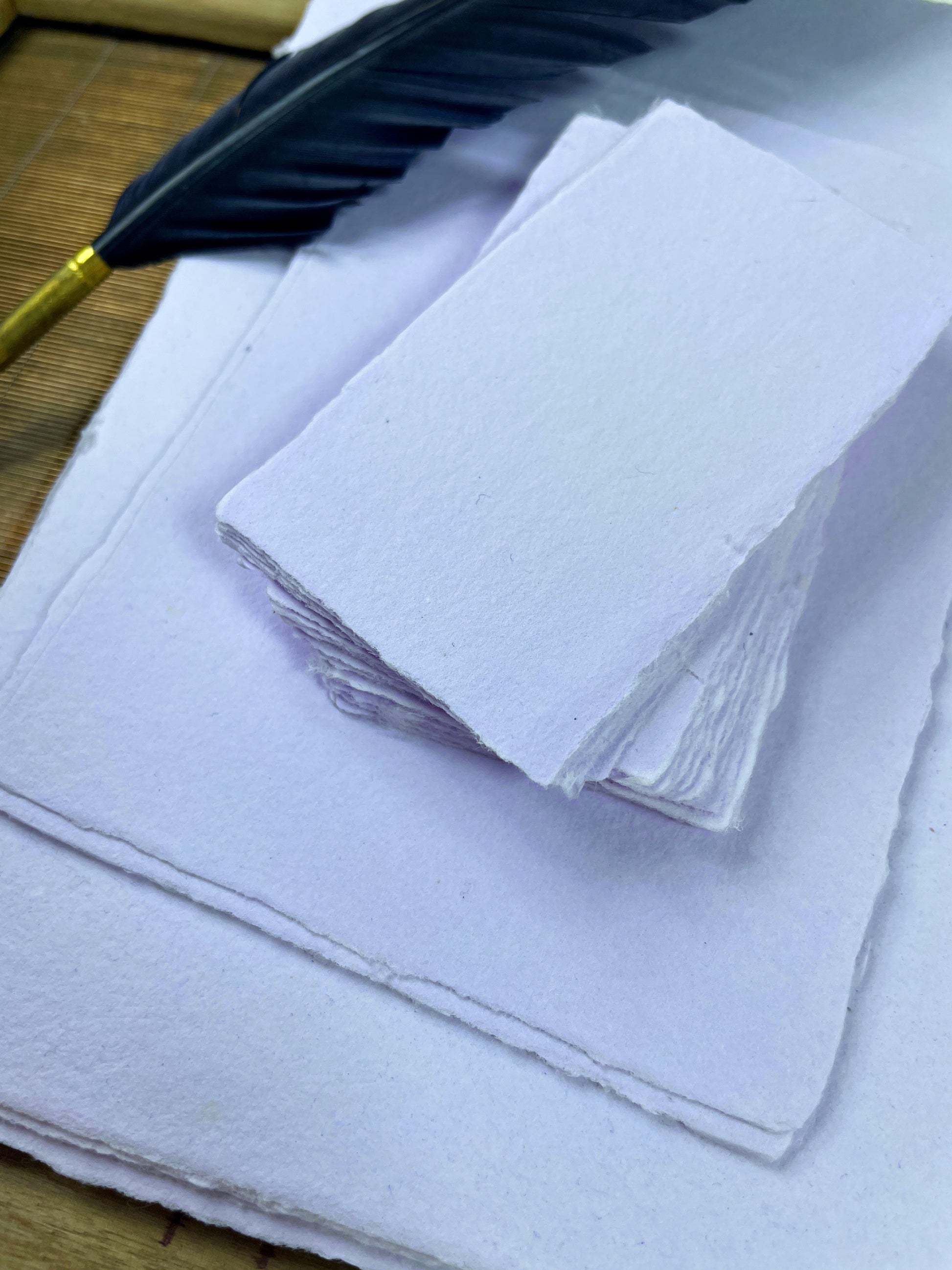 dekoratives Arrangement von violettem Büttenpapier mit Schreibfeder 