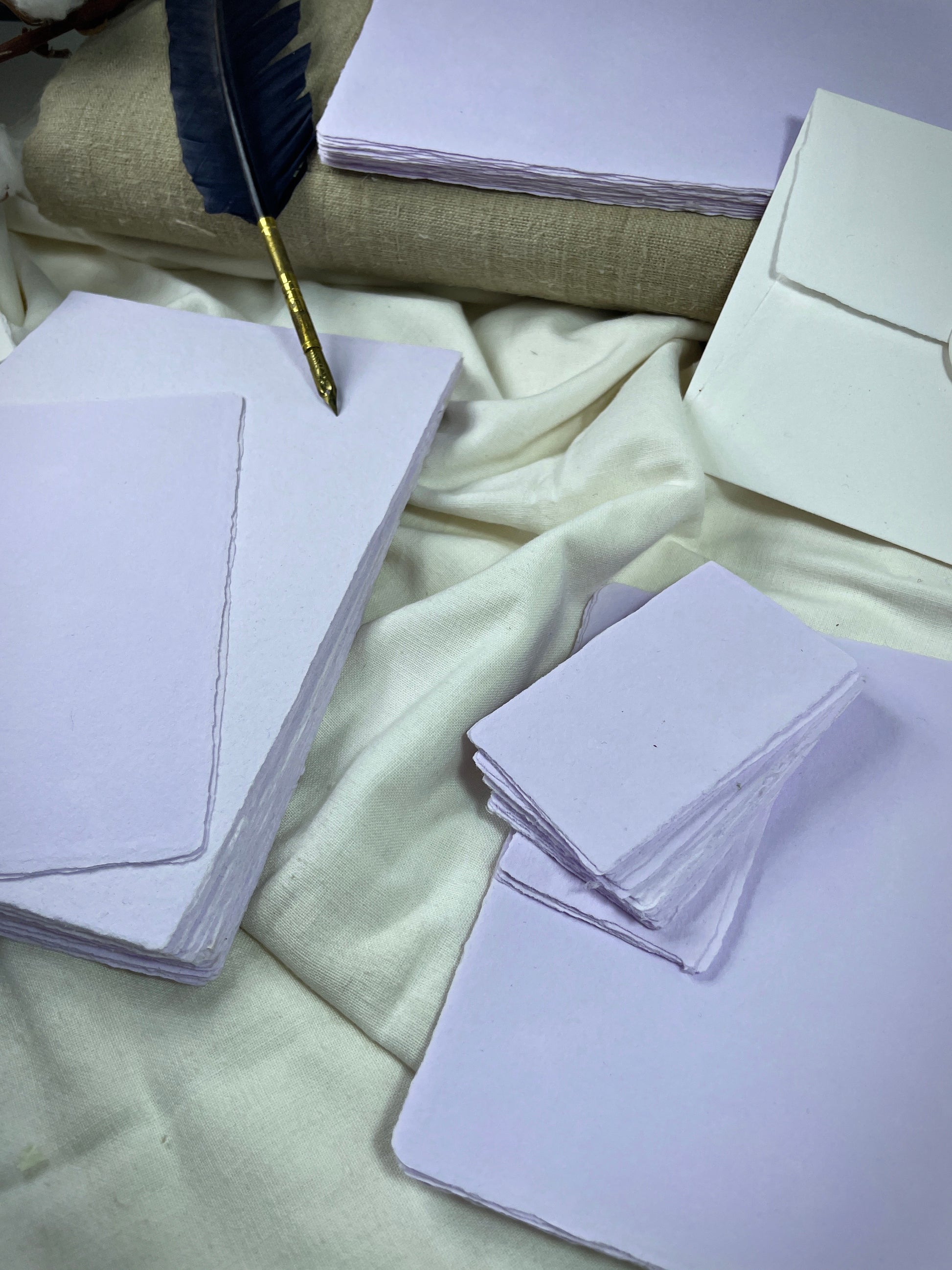 dekoratives Arrangement von violettem Büttenpapier mit Schreibfeder