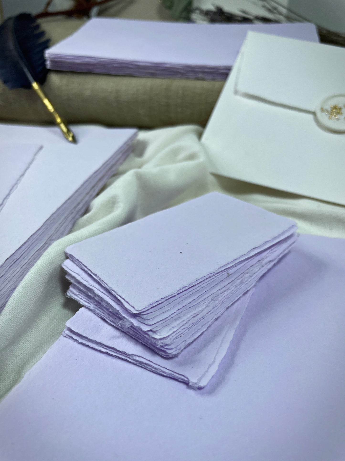 dekoratives Arrangement von violettem Büttenpapier mit Schreibfeder
