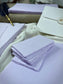 dekoratives Arrangement von violettem Büttenpapier mit Schreibfeder