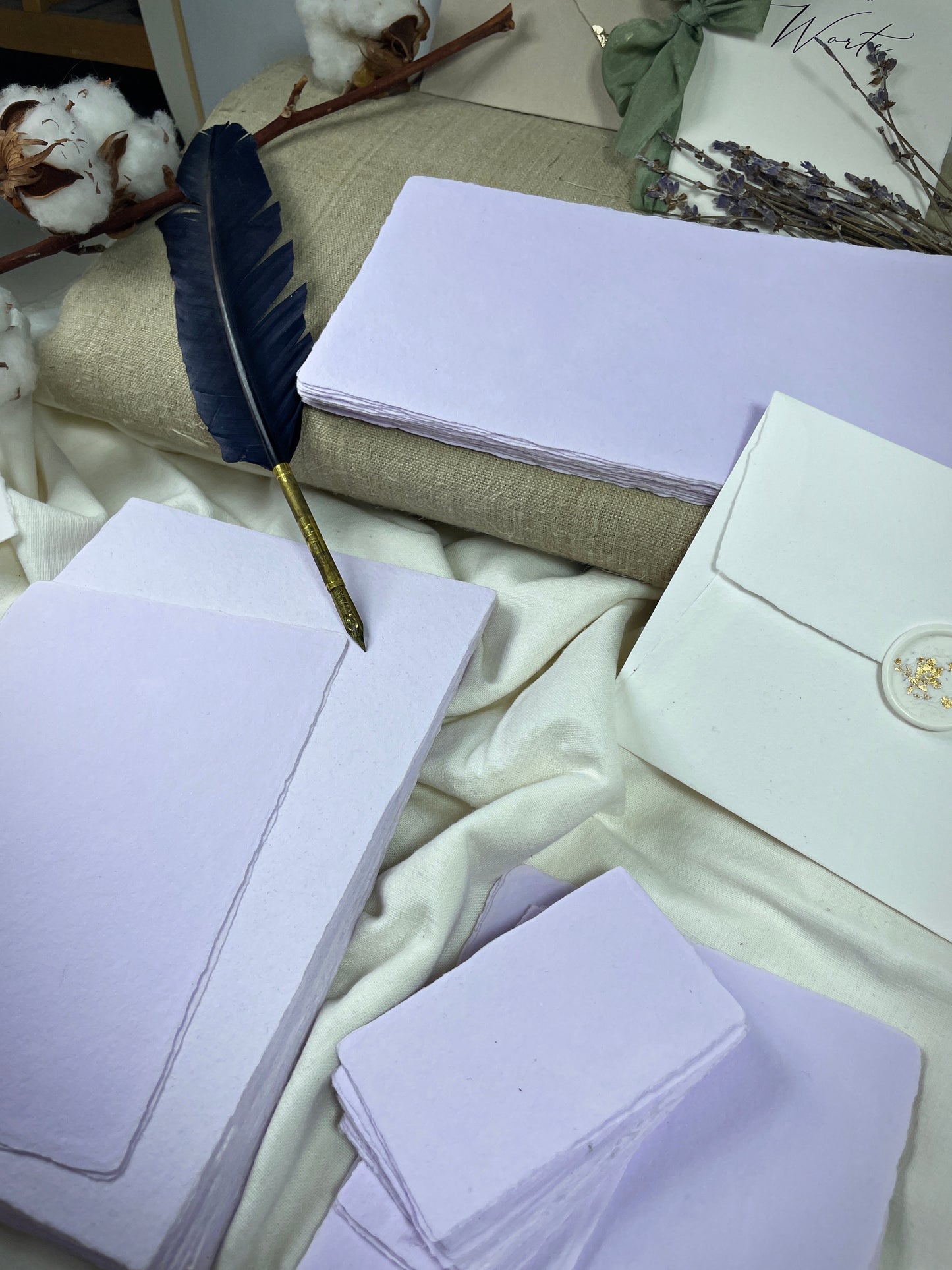 dekoratives Arrangement von violettem Büttenpapier mit Schreibfeder