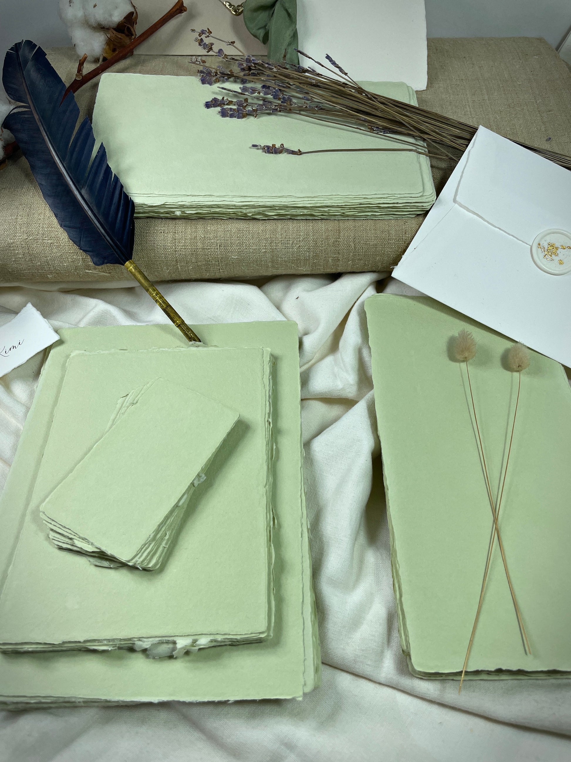 dekoratives Arrangement von grünem Büttenpapier mit Schreibfeder