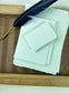 dekoratives Arrangement von mintfarbenem Büttenpapier mit Schreibfeder