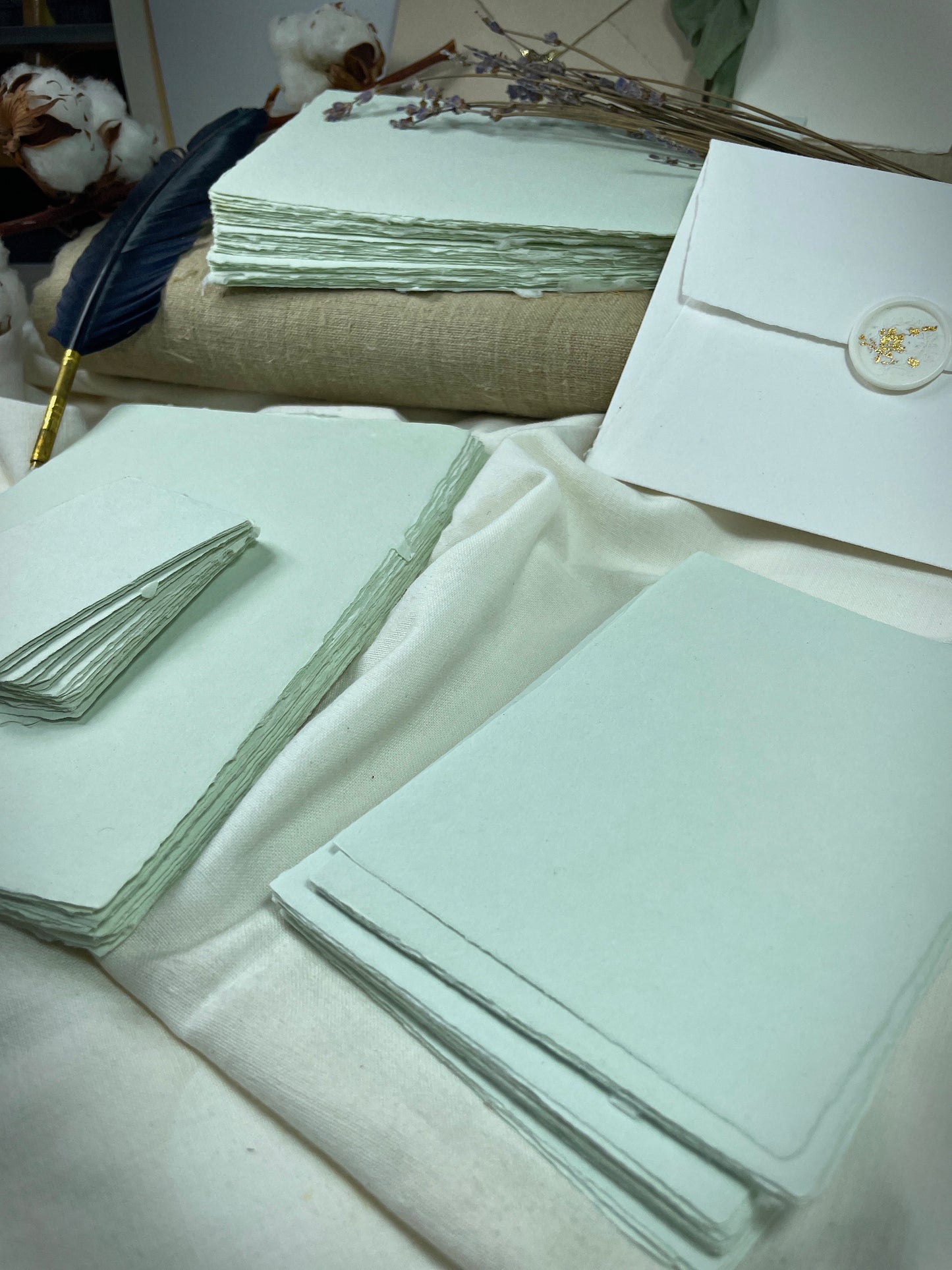 dekoratives Arrangement von mintfarbenem Büttenpapier mit Schreibfeder