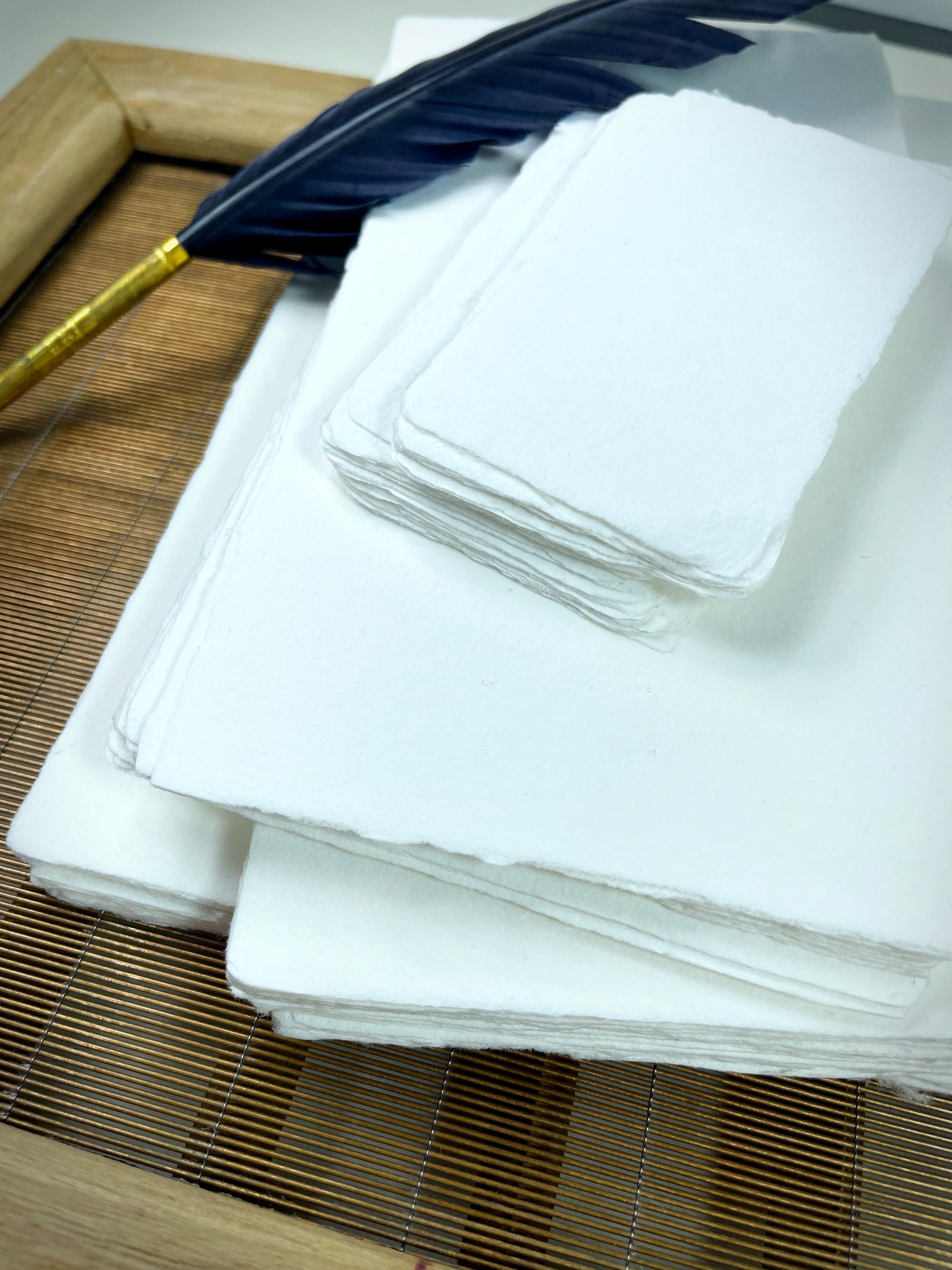 dekoratives Arrangement von weißem handgeschöpften Büttenpapier mit Schreibfeder
