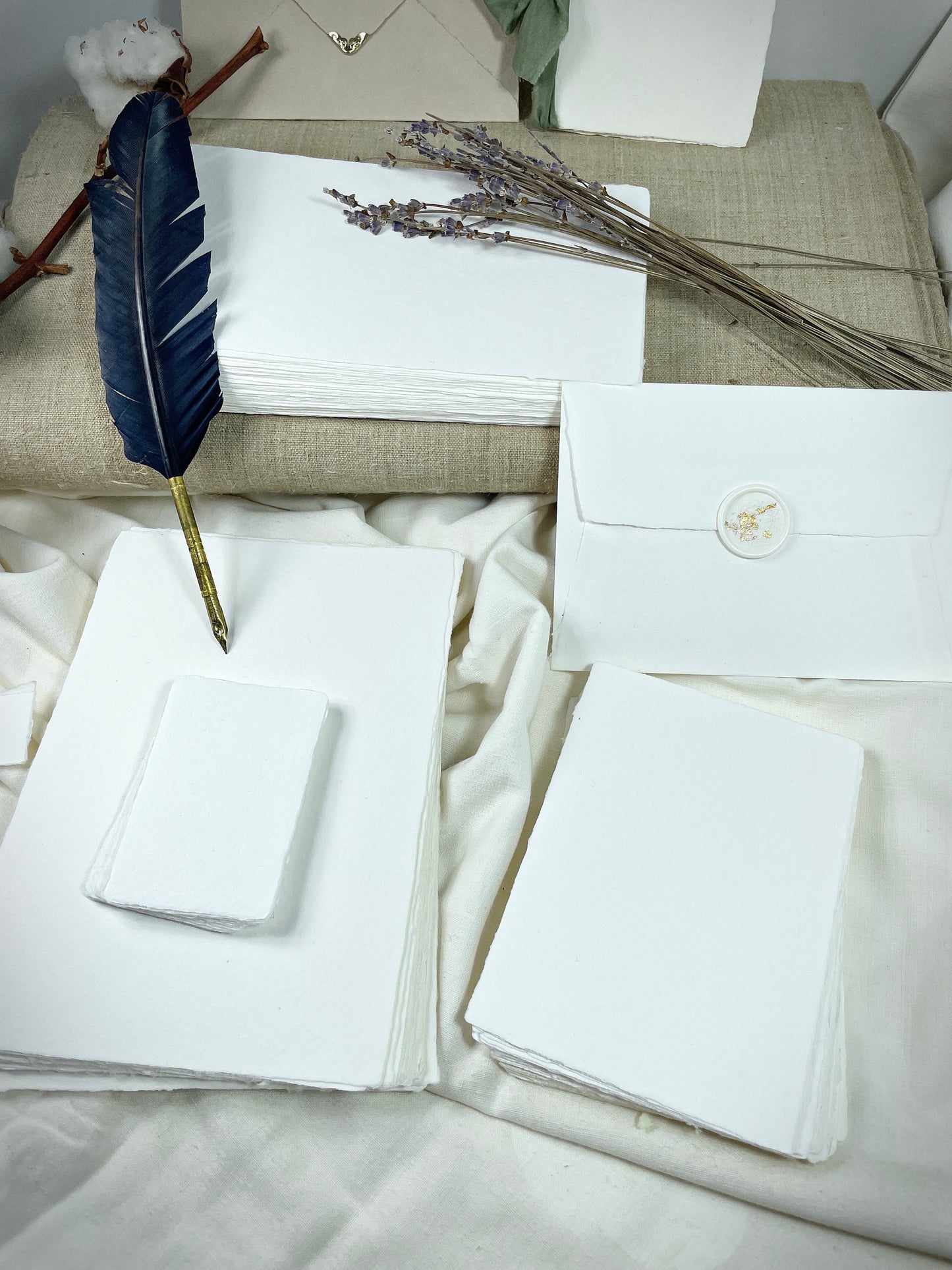 dekoratives Arrangement von weißem handgeschöpften Büttenpapier mit Schreibfeder