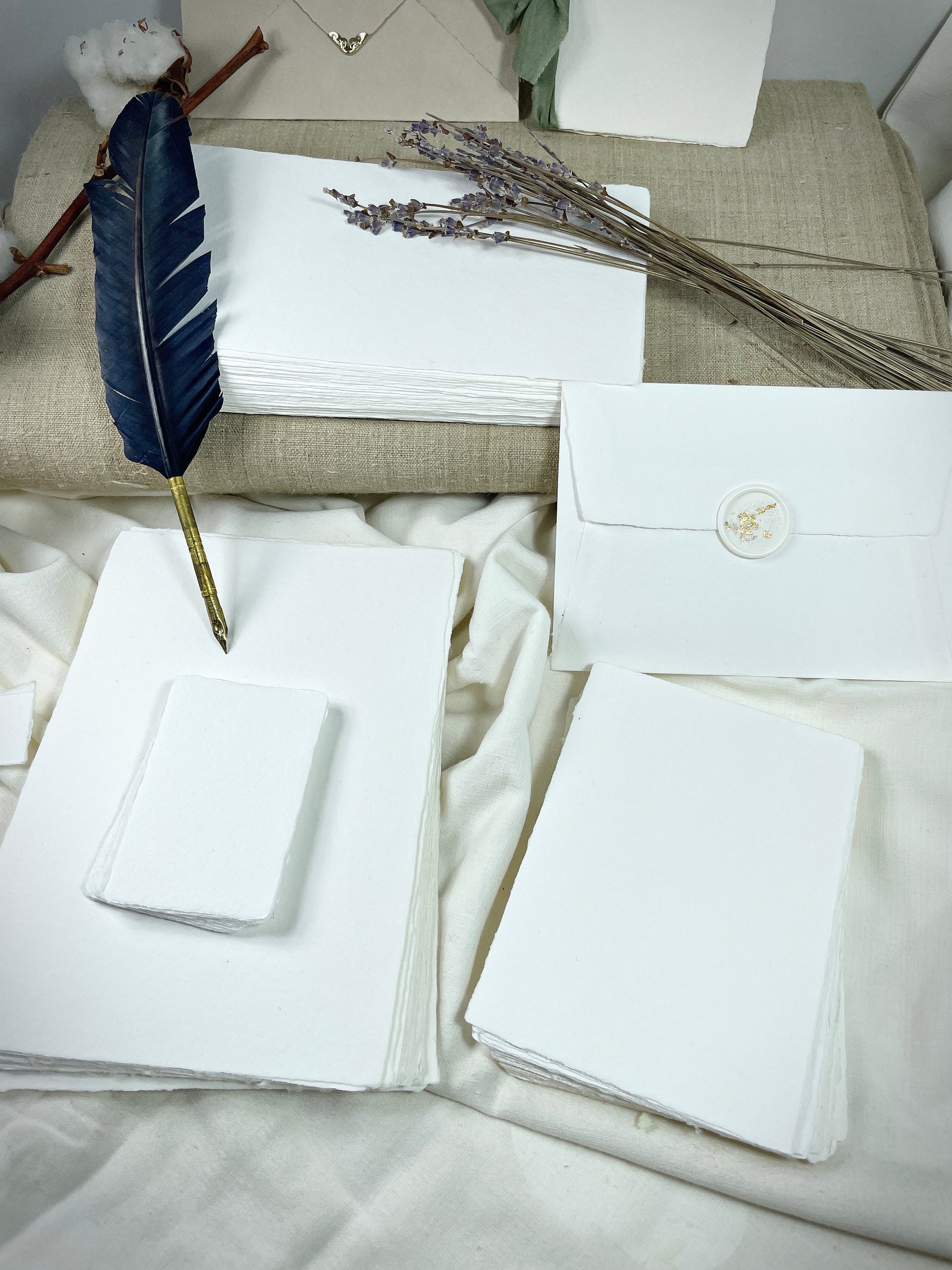 dekoratives Arrangement von weißem handgeschöpften Büttenpapier mit Schreibfeder