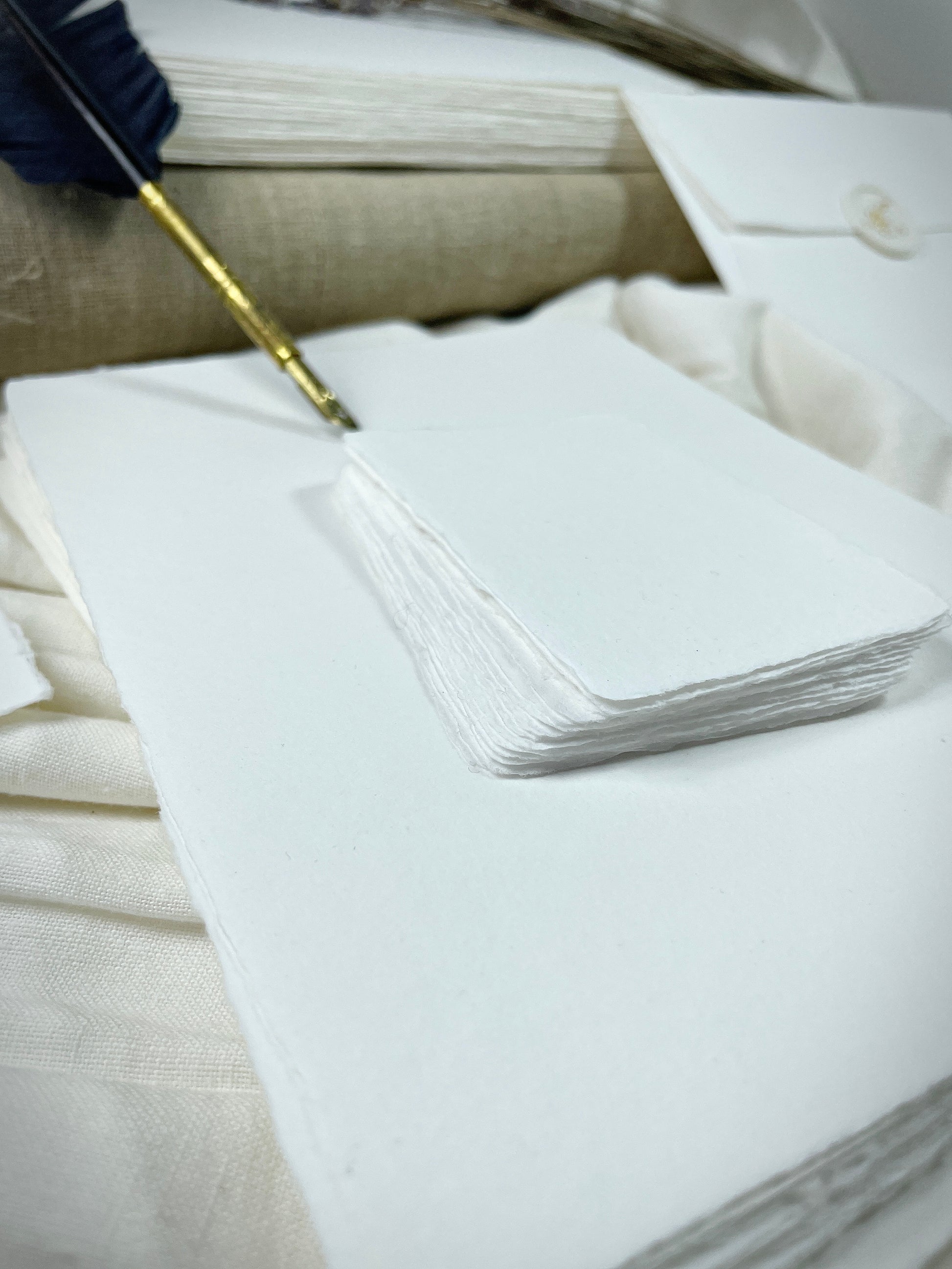 dekoratives Arrangement von weißem handgeschöpften Büttenpapier mit Schreibfeder