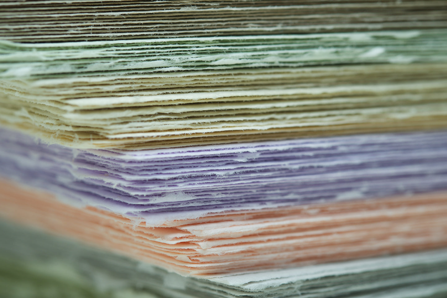 Büttenpapierstapel mit bunten Papieren von der Seite mit großer tiefenunschärfe 