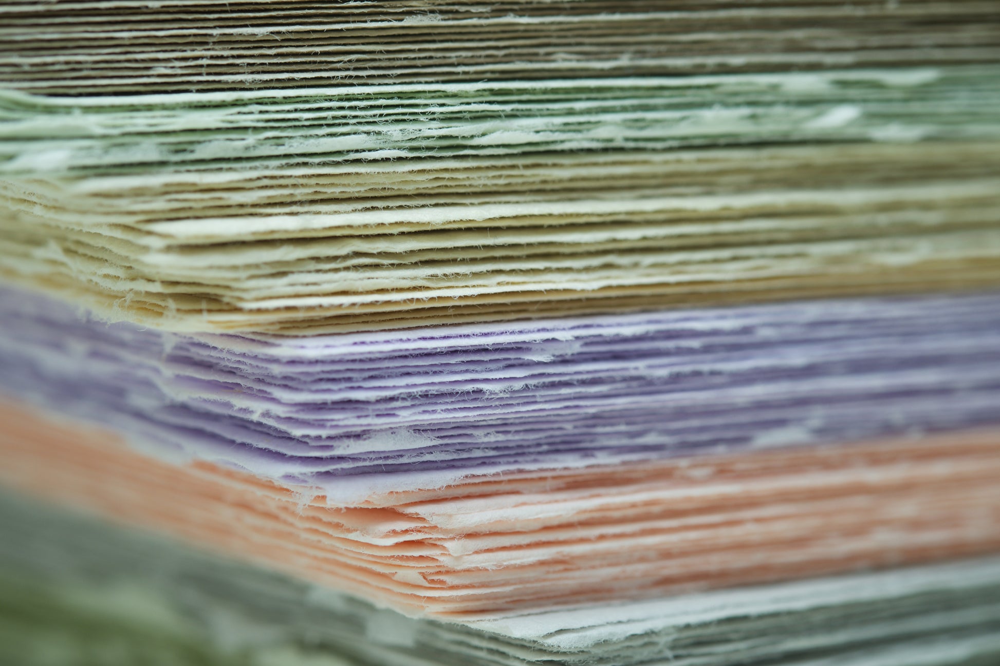 Büttenpapierstapel mit bunten Papieren von der Seite mit großer tiefenunschärfe 