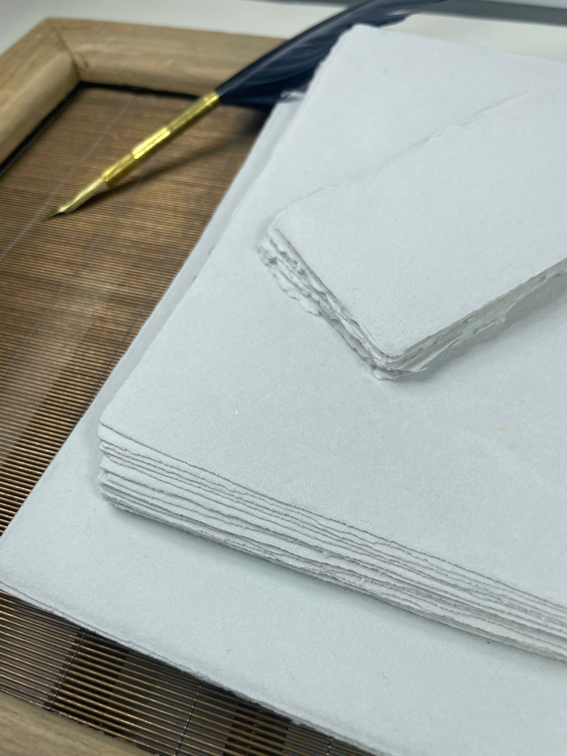 dekoratives Arrangement von grauem Büttenpapier mit Schreibfeder