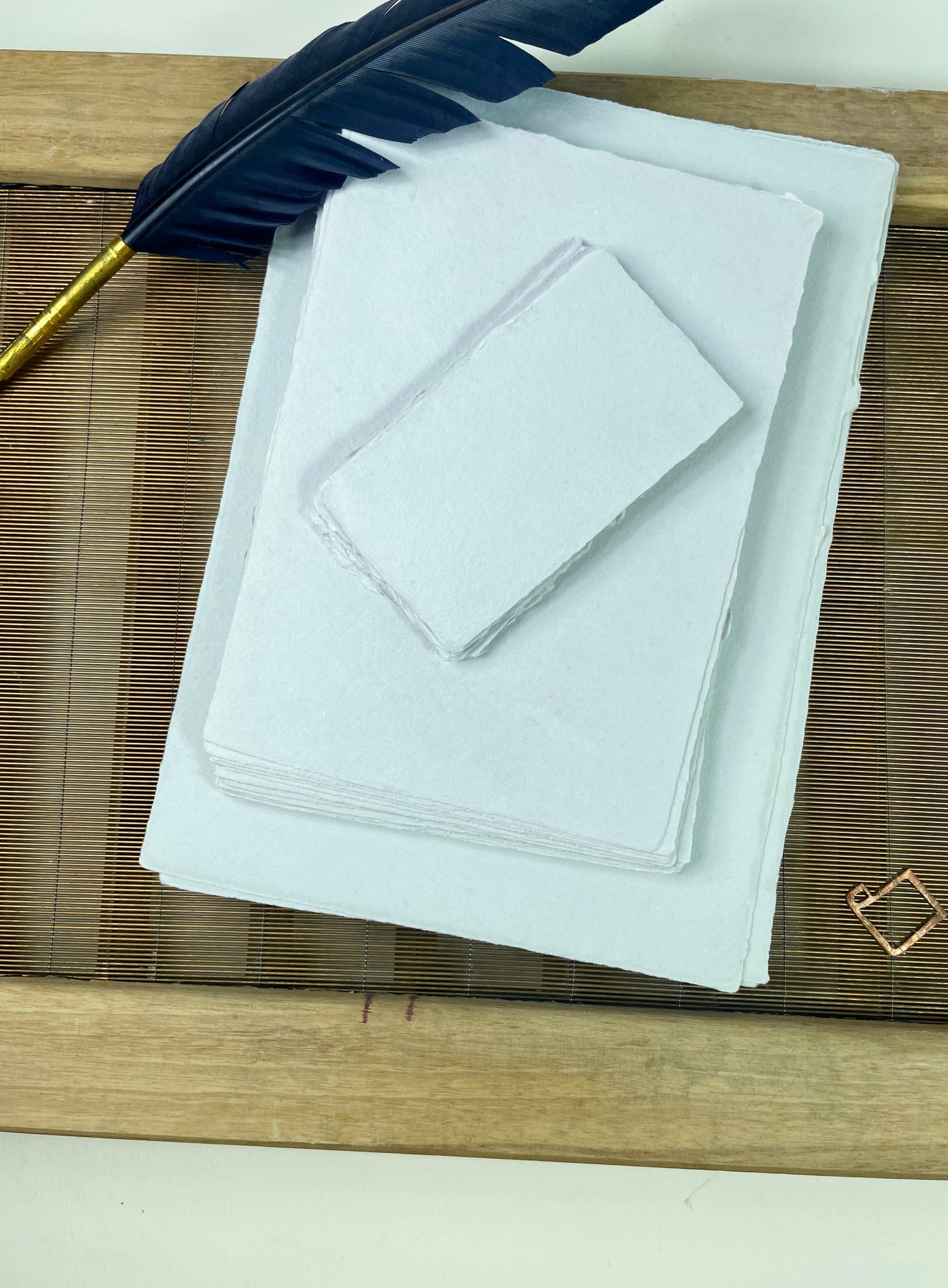 dekoratives Arrangement von grauem Büttenpapier mit Schreibfeder
