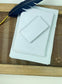 dekoratives Arrangement von grauem Büttenpapier mit Schreibfeder