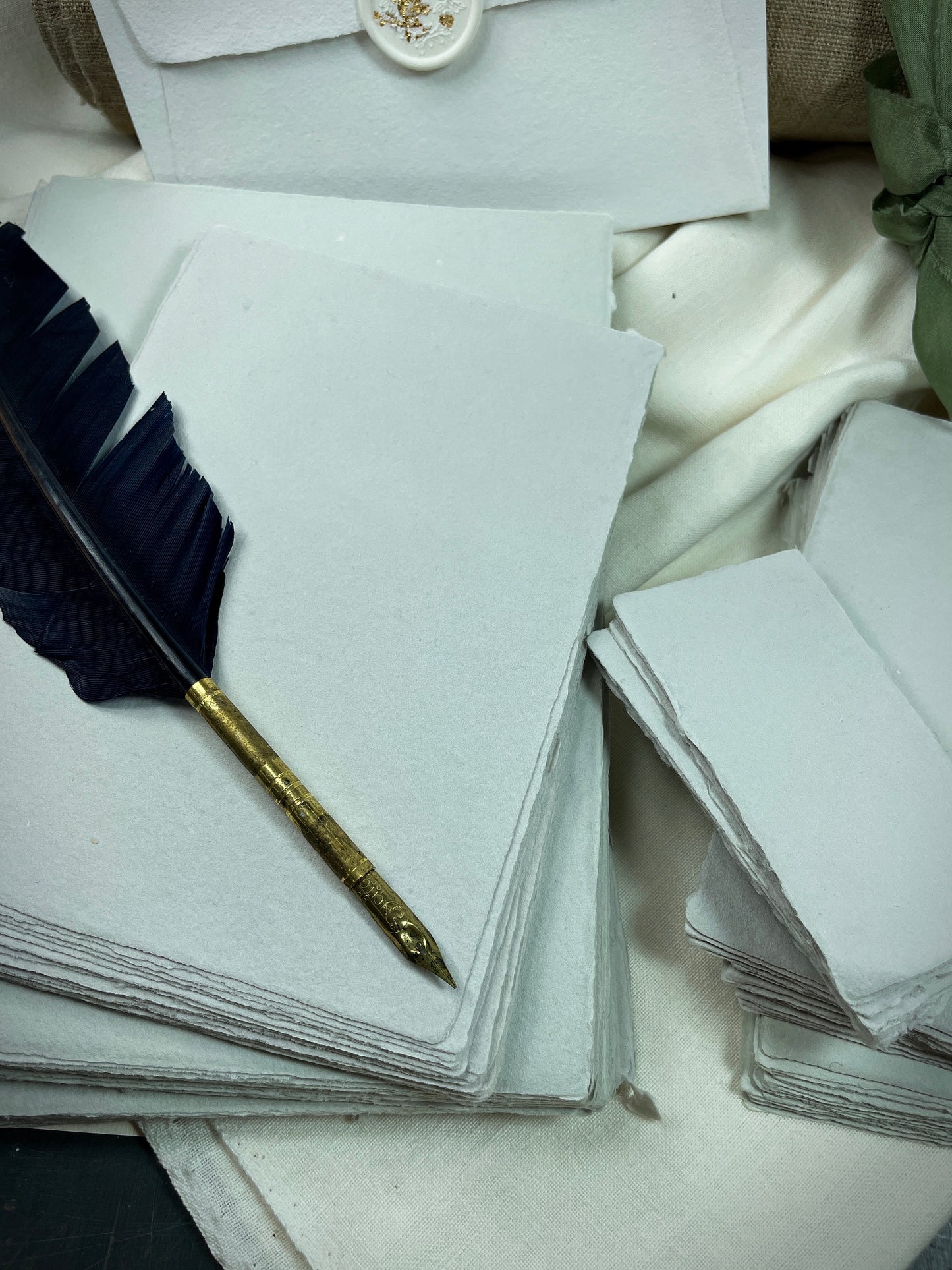 dekoratives Arrangement von grauem Büttenpapier mit Schreibfeder
