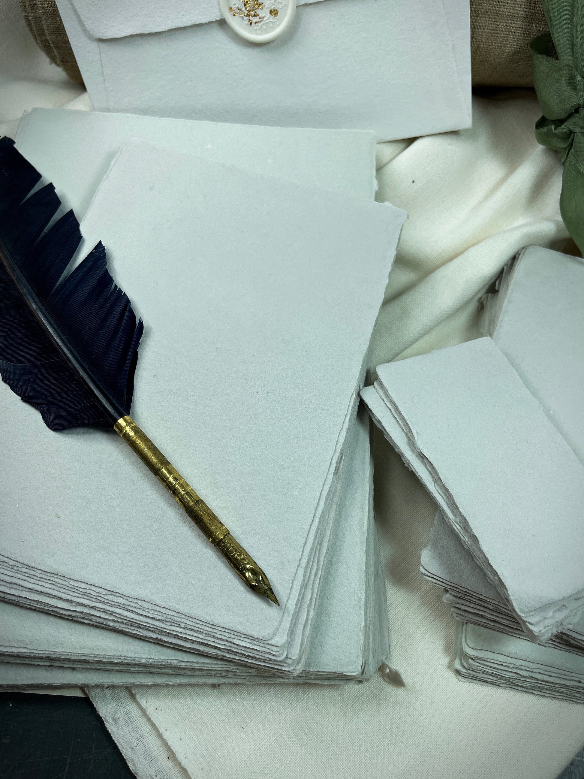 dekoratives Arrangement von grauem Büttenpapier mit Schreibfeder