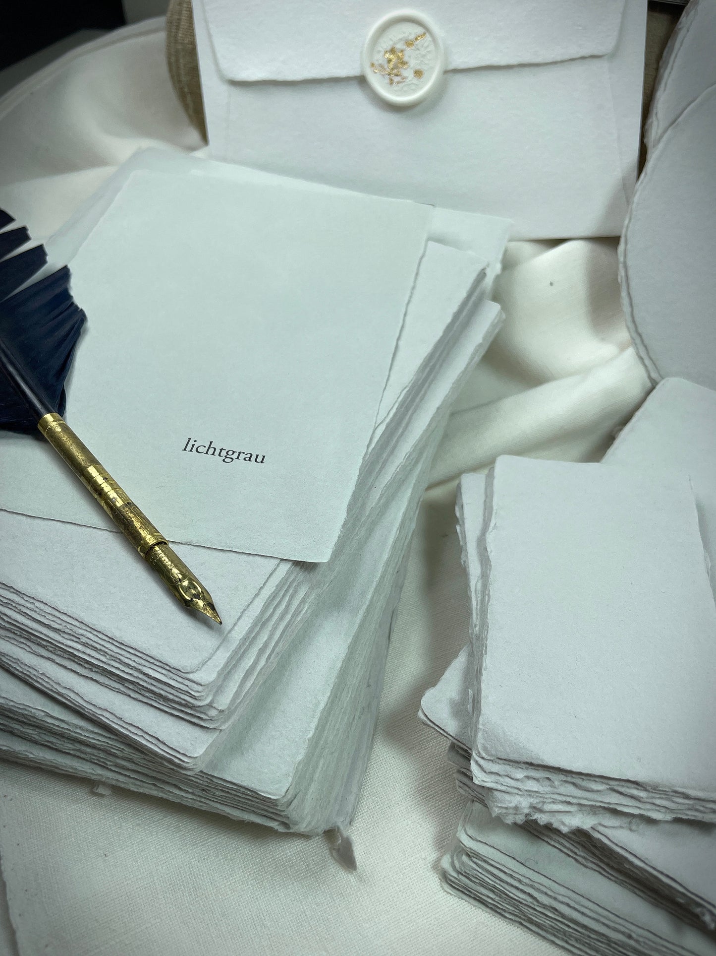 dekoratives Arrangement von grauem Büttenpapier mit Schreibfeder