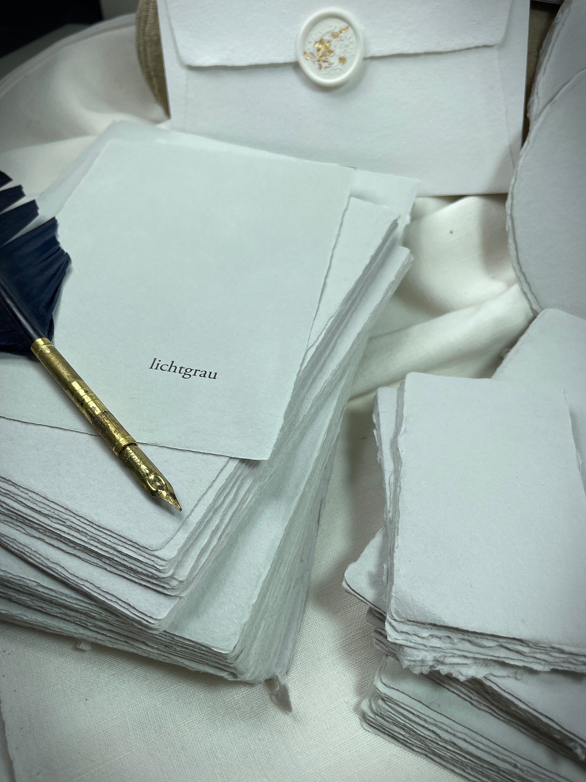 dekoratives Arrangement von grauem Büttenpapier mit Schreibfeder