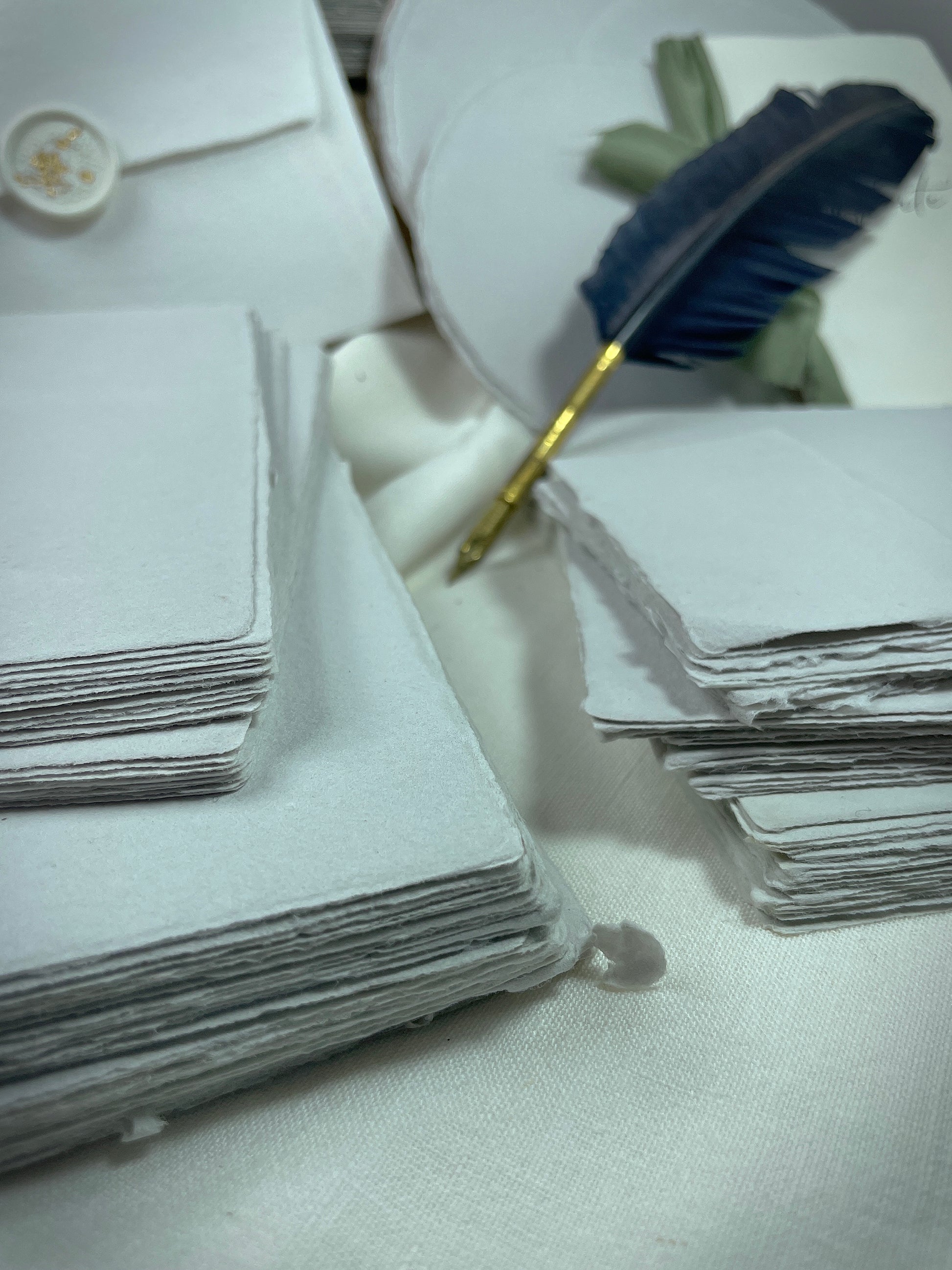 dekoratives Arrangement von grauem Büttenpapier mit Schreibfeder