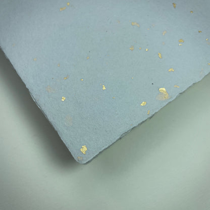 Detail eines Büttenpapiers mit eingeschöpften Goldflocken im Farbton lichtgrau