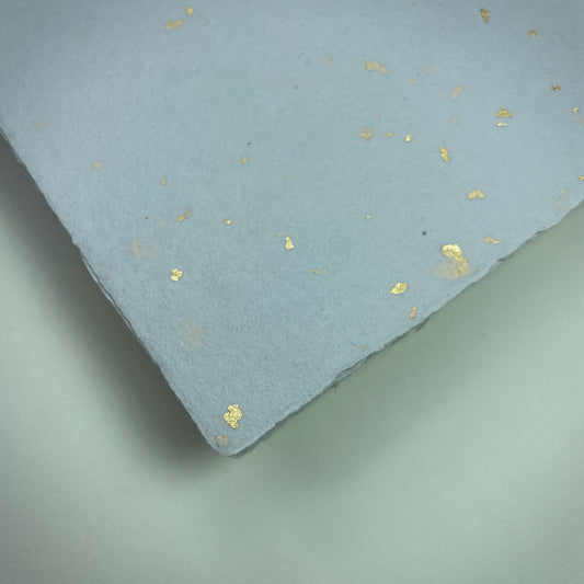 Detail eines Büttenpapiers mit eingeschöpften Goldflocken im Farbton lichtgrau