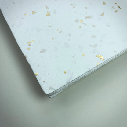 Detail eines Büttenpapiers mit eingeschöpften Goldflocken im Farbton naturweiß
