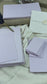 dekoratives Arrangement von violettem Büttenpapier mit Schreibfeder und Blumen