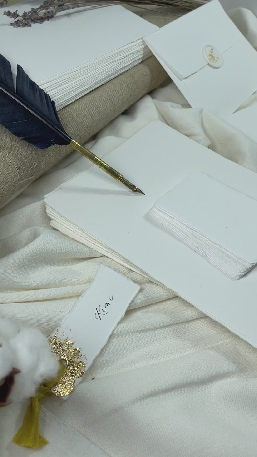 dekoratives Arrangement von weißem Büttenpapier mit Schreibfeder und Blumen