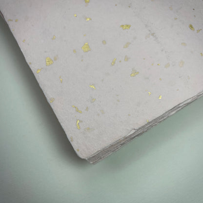 Detail eines Büttenpapiers mit eingeschöpften Goldflocken im Farbton rosé
